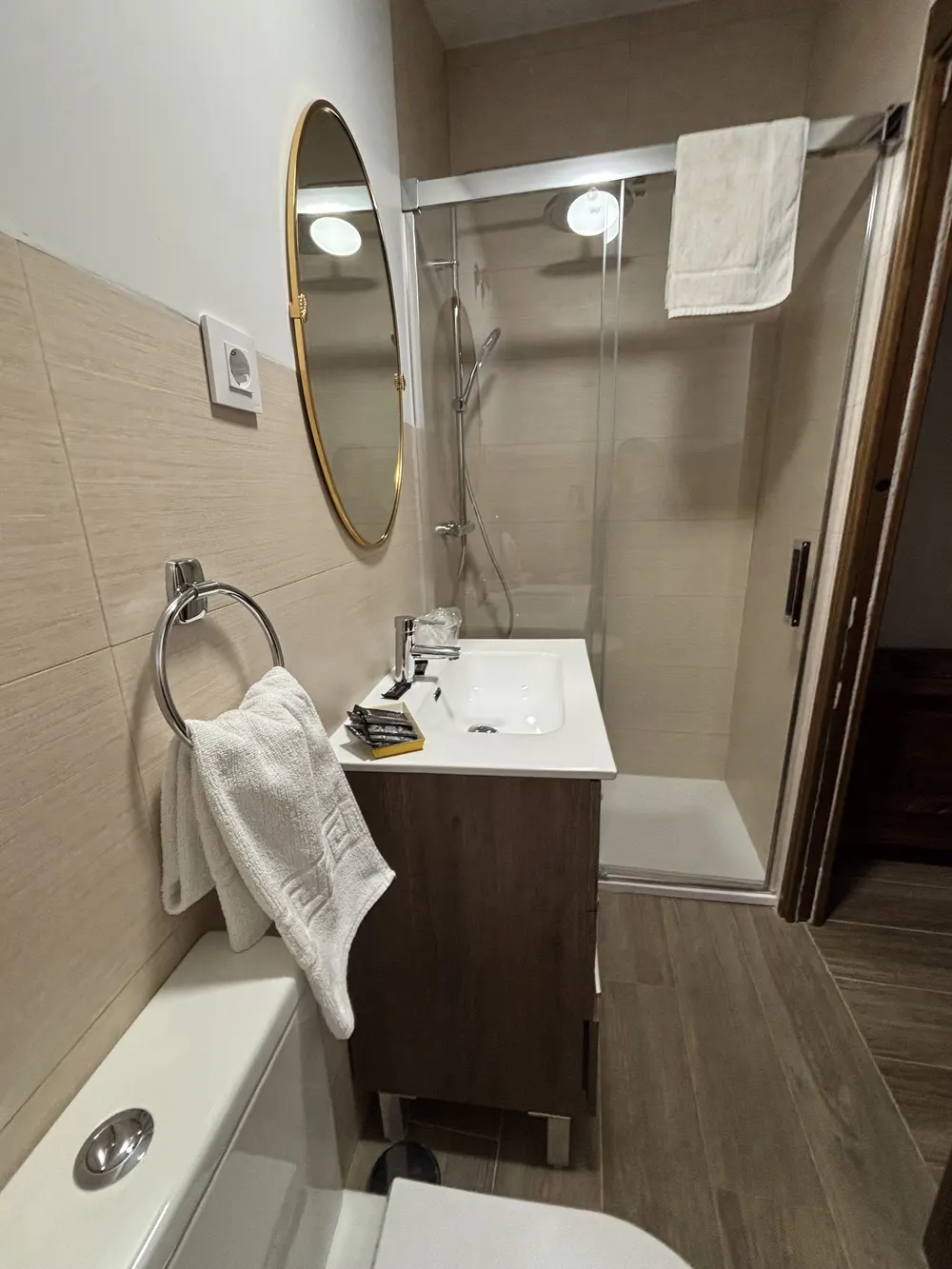 Baño con ducha, espejo redondo y mueble de madera