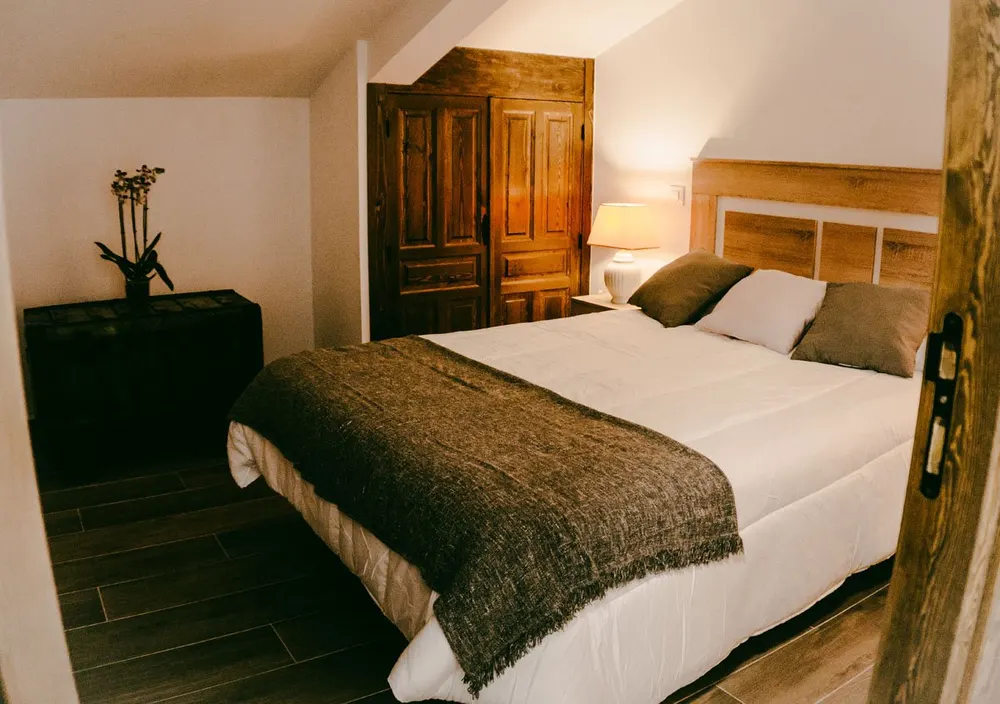 Dormitorio doble con cabecero de madera y armario antiguo