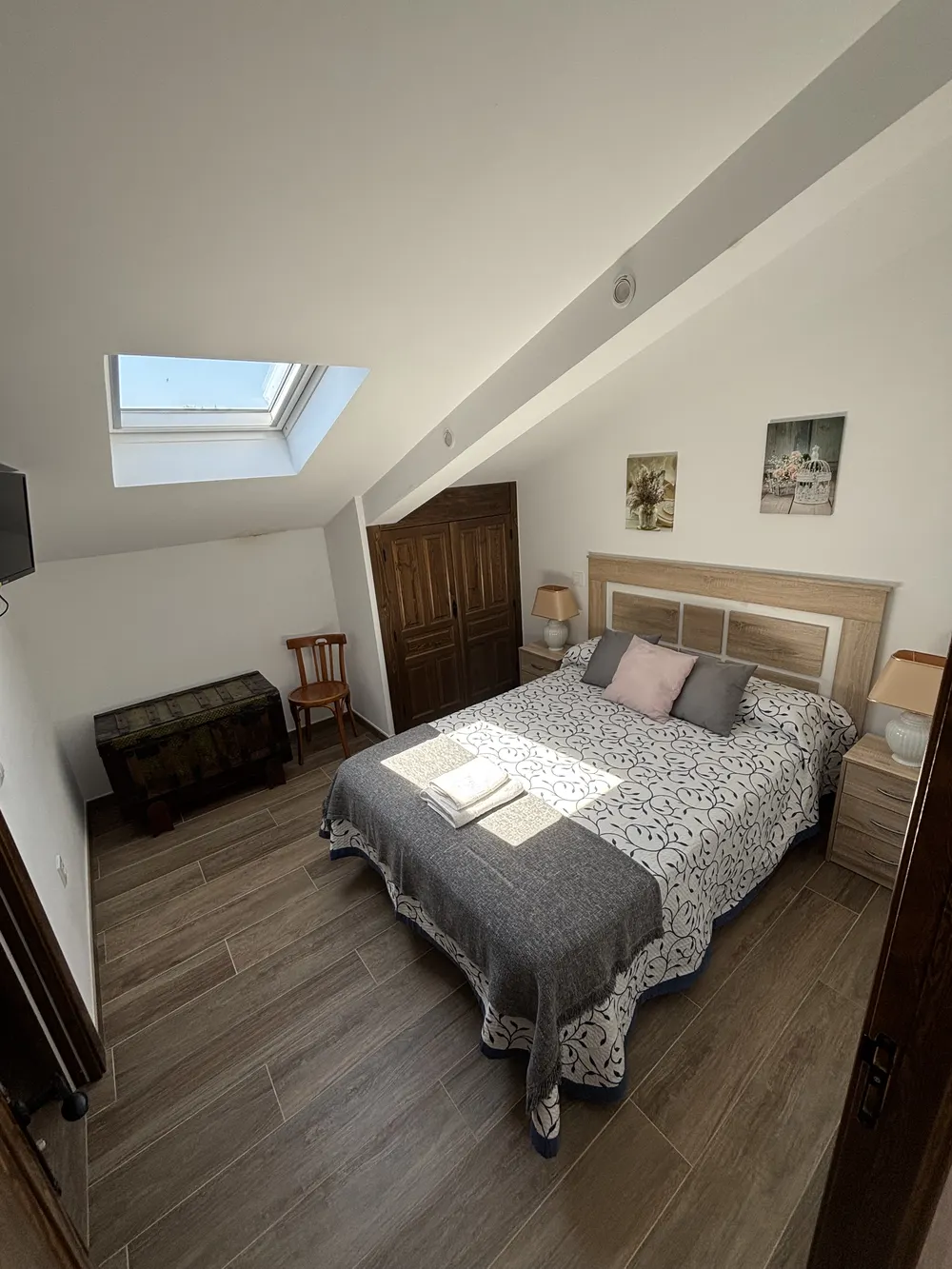 Dormitorio abuhardillado con claraboya y ropa de cama gris