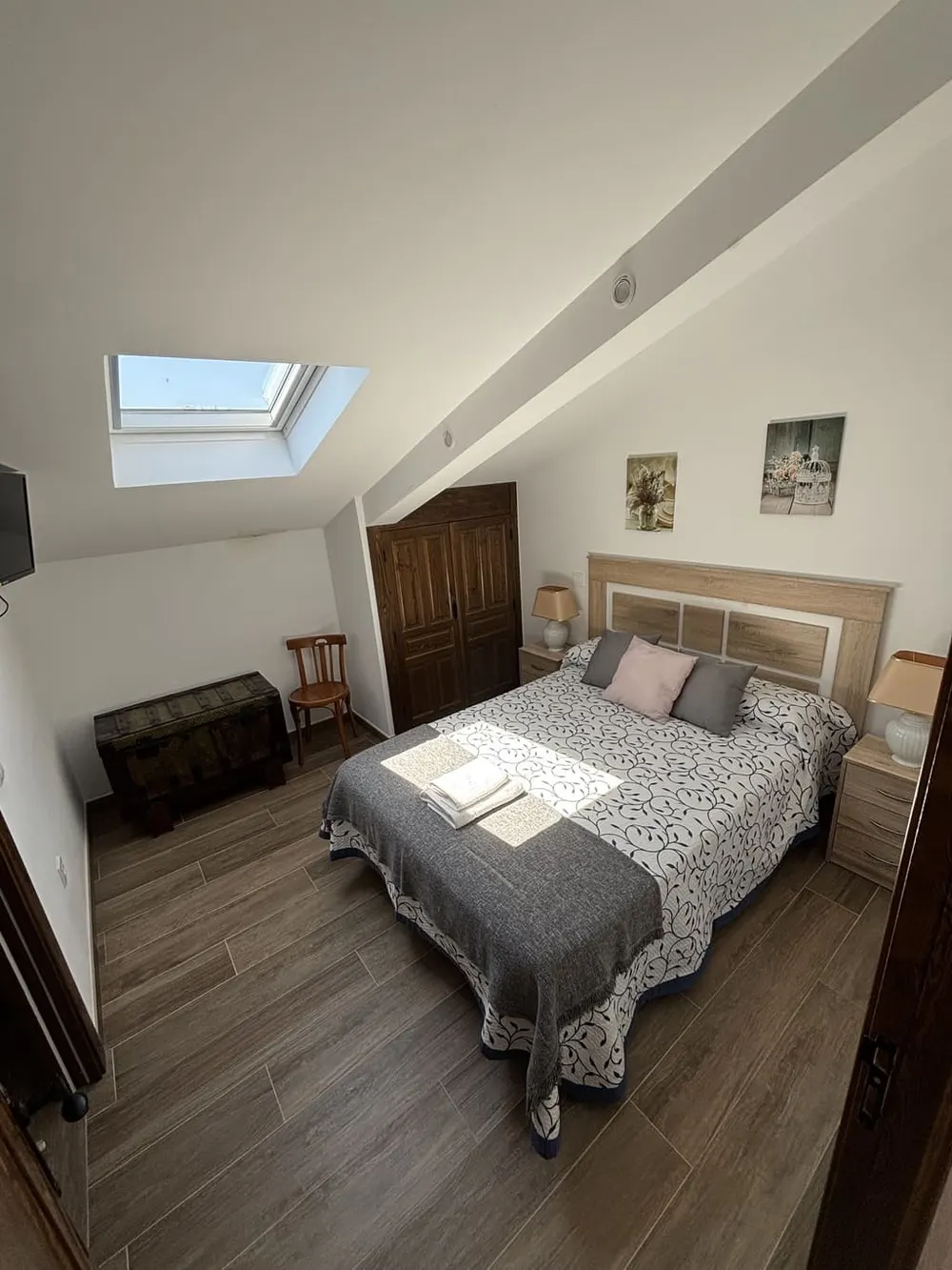 Dormitorio abuhardillado con claraboya y cama doble