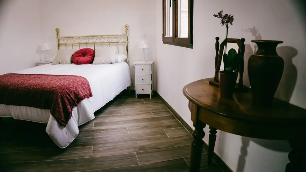 Dormitorio doble con colcha granate y mesa de madera