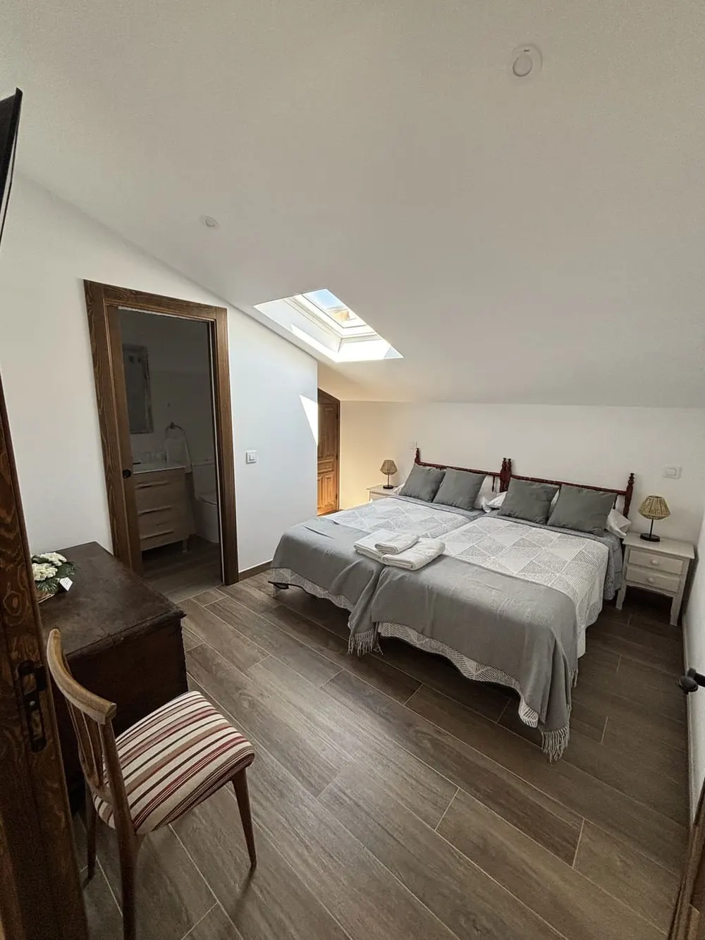 Dormitorio doble luminoso con silla de madera junto a la ventana