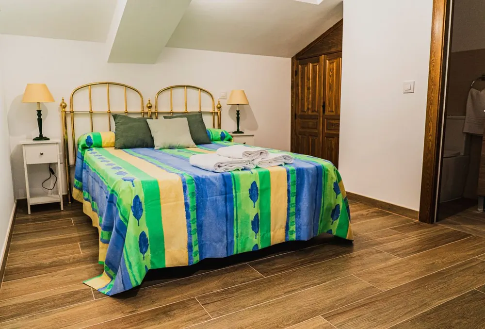 Dormitorio doble con colcha de rayas verdes y mesillas a juego