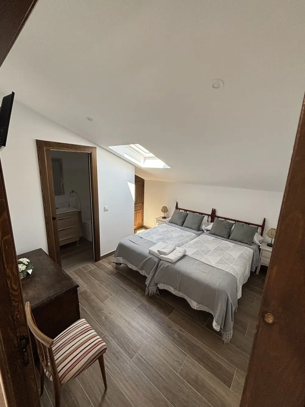 Dormitorio doble con ropa de cama blanca y silla de anea