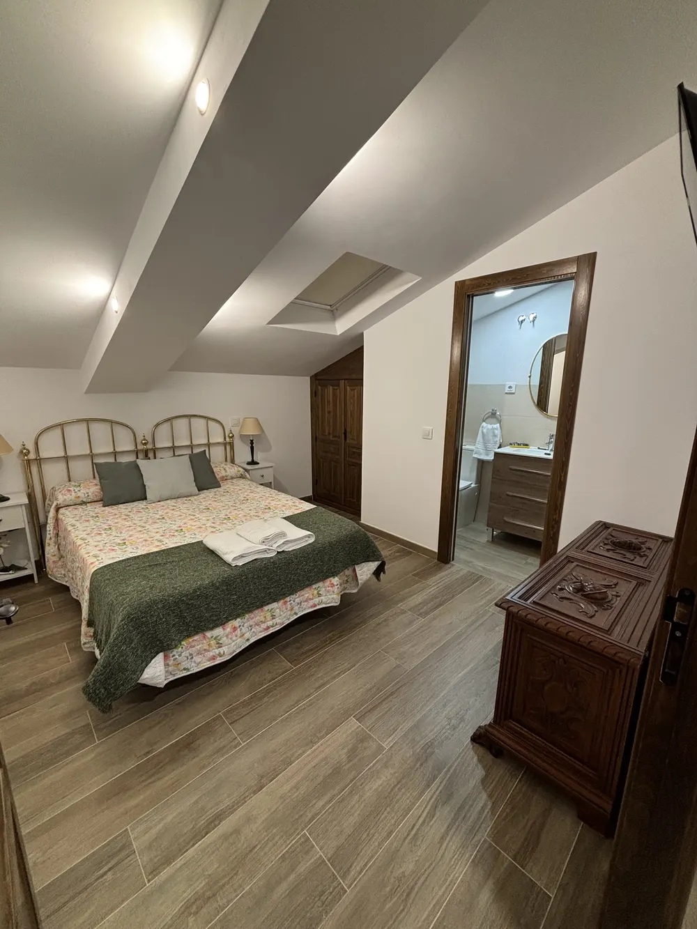 Dormitorio con colcha verde y baño privado al fondo