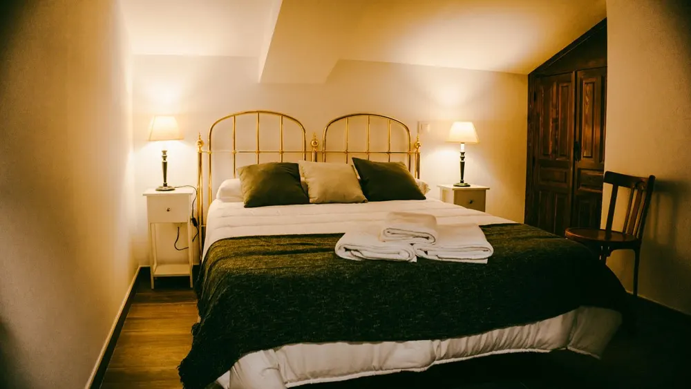 Dormitorio doble con cabecero de forja y colcha verde