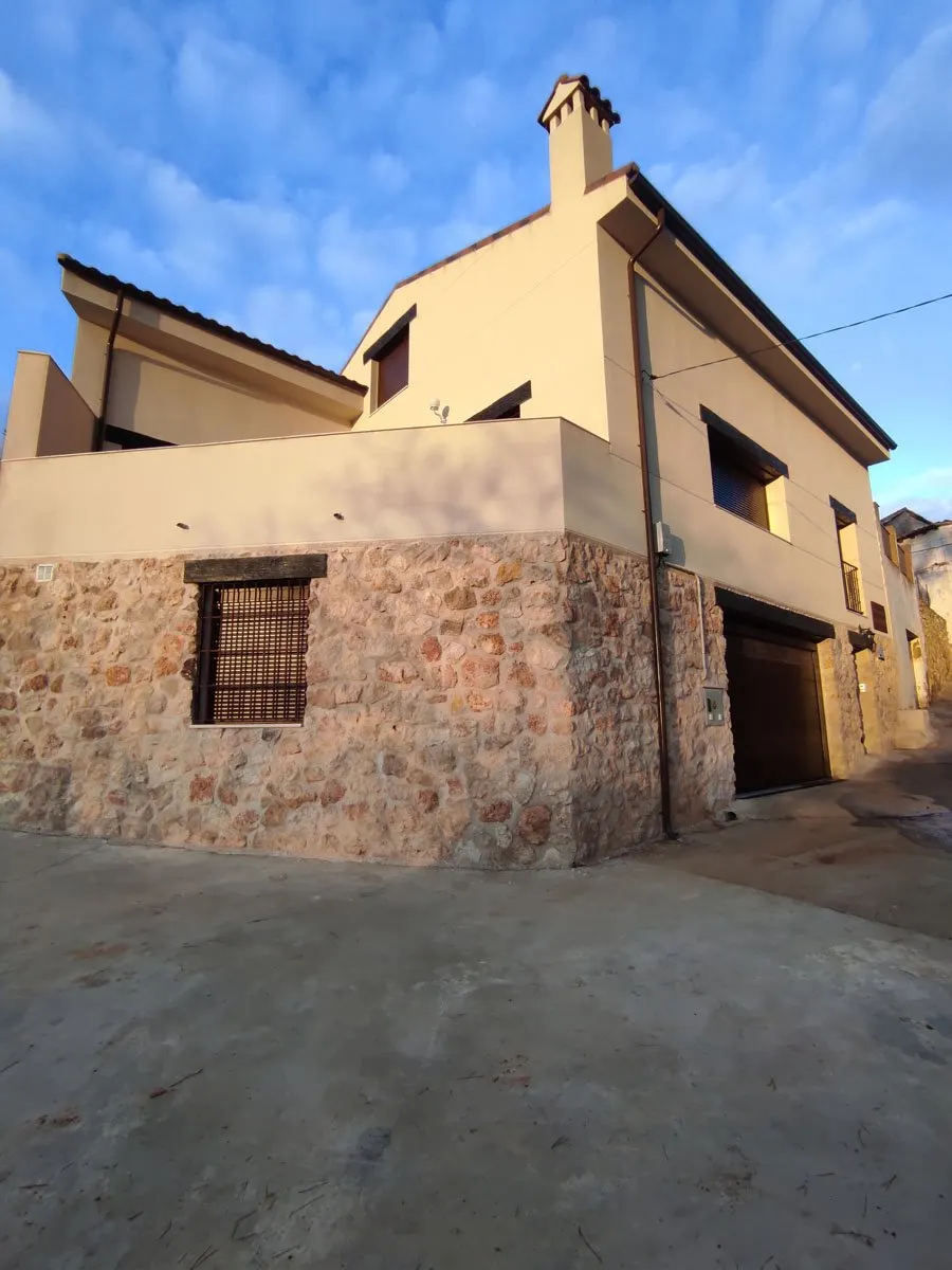 Fachada de la casa rural desde la calle, con muros de piedra