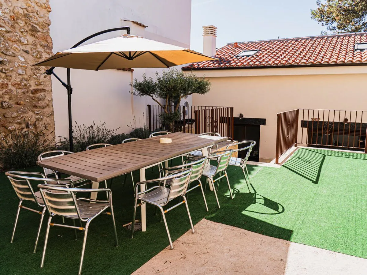 Patio exterior de El Aprisco con mesa larga para diez personas y sombrilla