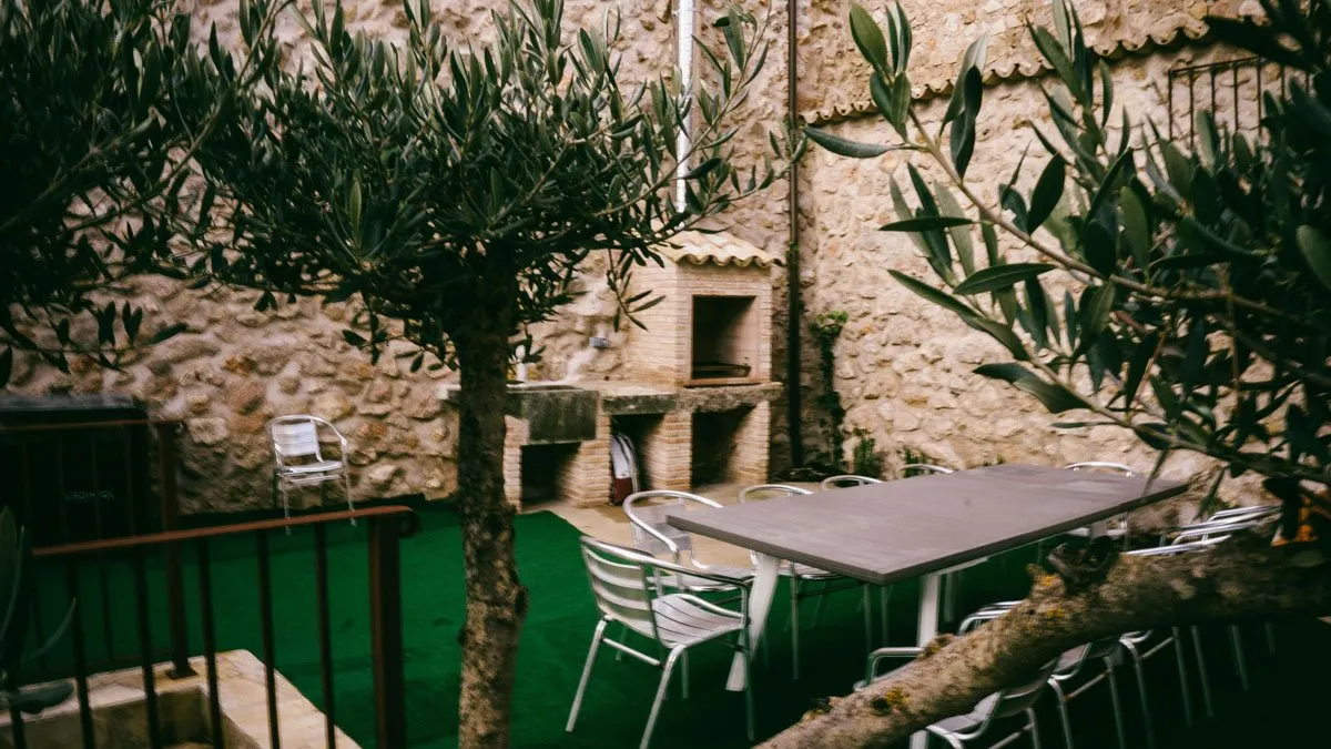 Patio privado con olivo, césped y barbacoa de obra en piedra