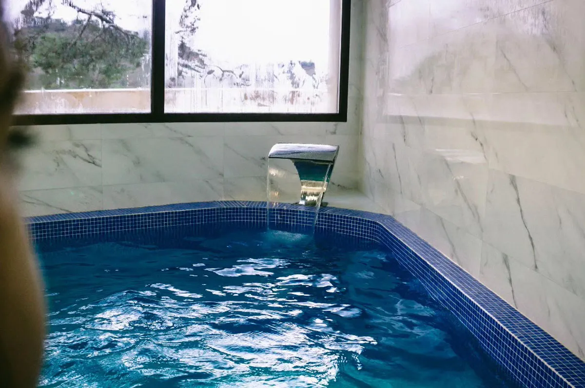Piscina climatizada cubierta con cascada de agua en Casa Rural El Aprisco