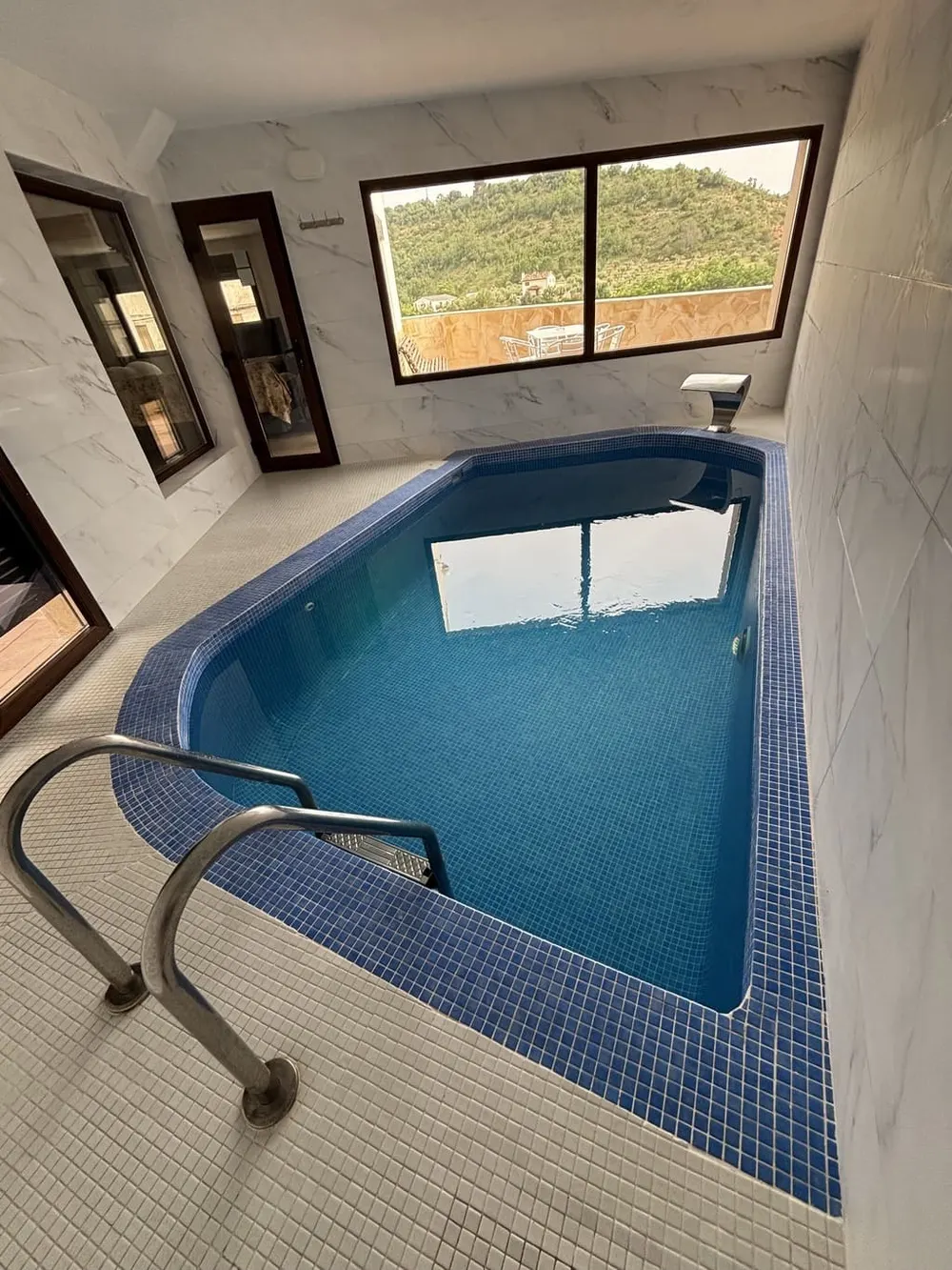 Vista general de la piscina climatizada con escalera de acero