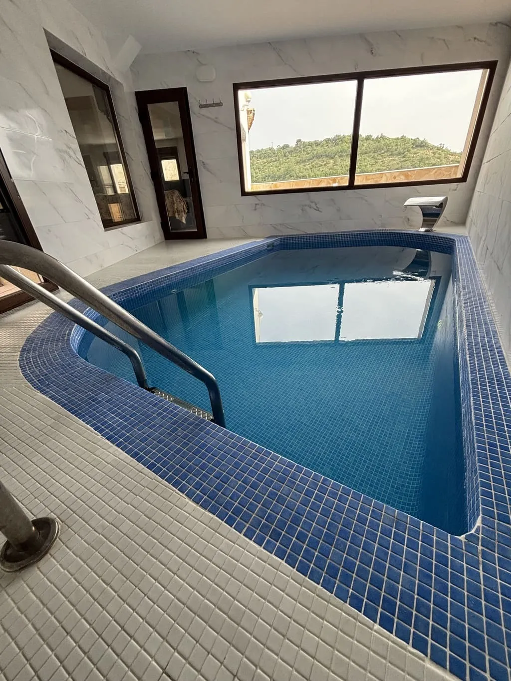 Piscina climatizada cubierta de Casa Rural El Aprisco con ventanal a la montaña