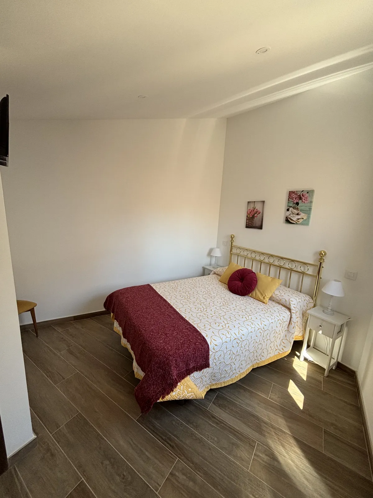 Dormitorio de la suite con colcha granate y cojines amarillos